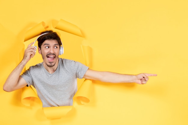 young man in headphones with excited face on a torn yellow background music ultrasound sound audio