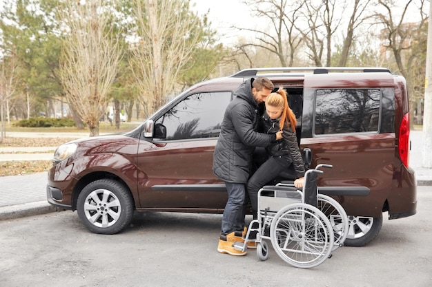 Young man helping handicapped woman to sit in wheelchair