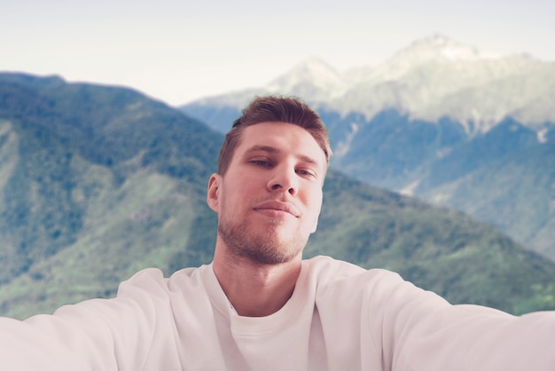 A young man hiking the mountain, making a self portrait on the mountain peak