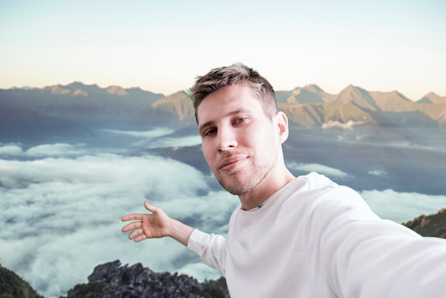 A young man hiking the mountain, making a self portrait on the mountain peak