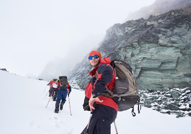 友達と冬の山でハイキングする若い男