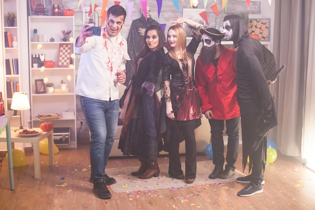 Young man and his friends are taking a selfie at halloween party in their costumes.