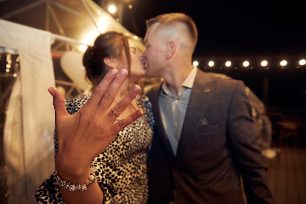 Young man and his happy fiancee showing engagement ring