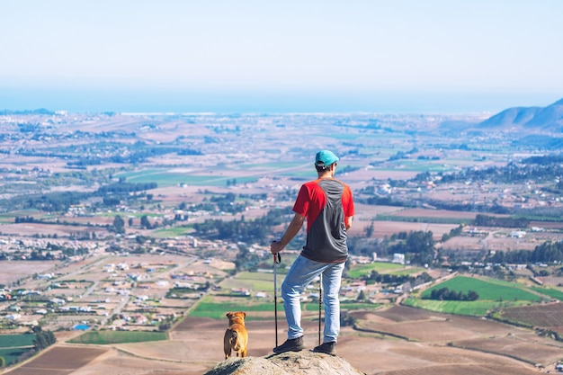 young man and his pet standing o the mountain above the city staring the horizon