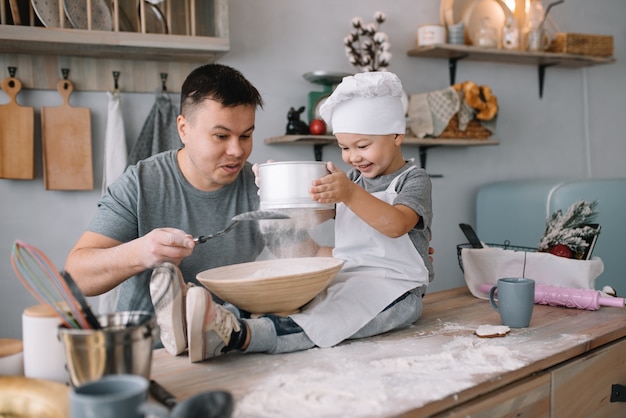 Photo young man and his son playing in the kitchen