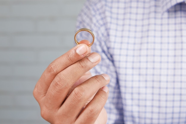 若い男はコピースペースで結婚指輪を保持します