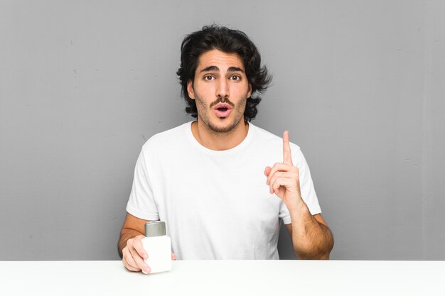 Young man holding an aftershave cream having some great idea, concept of creativity.