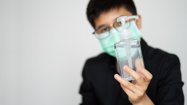 young man holding algohal gel bottle wearing face hygienic mask for prevention contagious covid-19 virus pandemic.