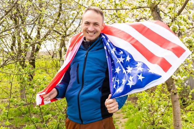 Young man holding american national flag to the sky with two hands.