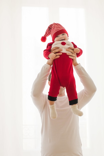 Giovane che tiene bambino in pagliaccetto di natale