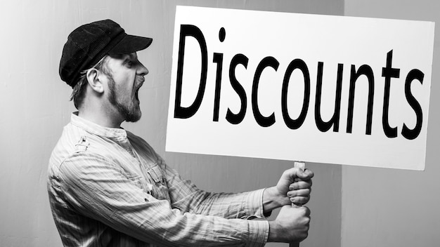 Photo young man holding a banner with discounts inscription