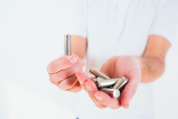 Young man holding batteries in his  hands. Recycling time. Metal lithium no waste lifestyle.