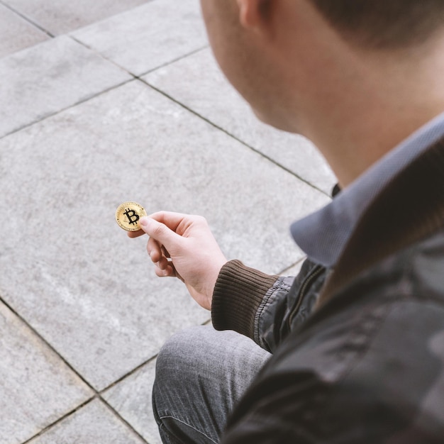 Young man holding bitcoin coin in his hand