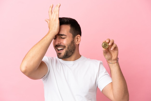 Young man holding a Bitcoin isolated on pink background has realized something and intending the solution