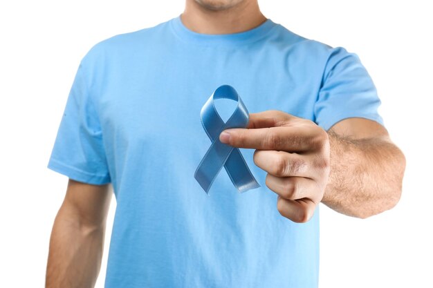 Young man holding blue ribbon on white background Cancer concept