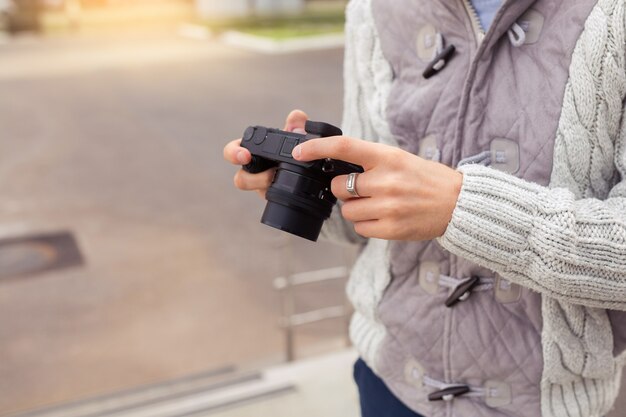 カメラを持って、彼の写真撮影のための興味深い被写体を探している若い男、クローズアップ