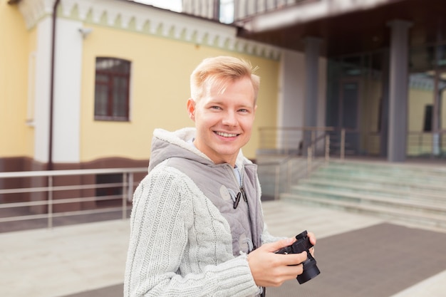 Young man holding camera and searching for an interesting\
subject for his photo shooting