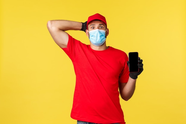 Young man holding camera while standing against yellow background