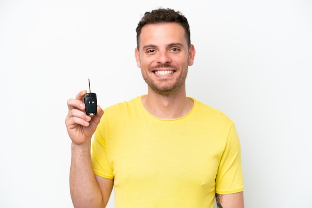 Young man holding car keys isolated on white background smiling a lot