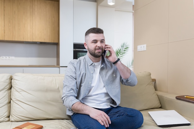  Young man holding credit card and using phone at home office