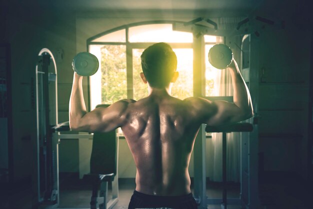 Young man holding dumbbells at gym