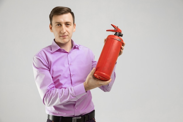 Young man holding a fire extinguisher in his hands 