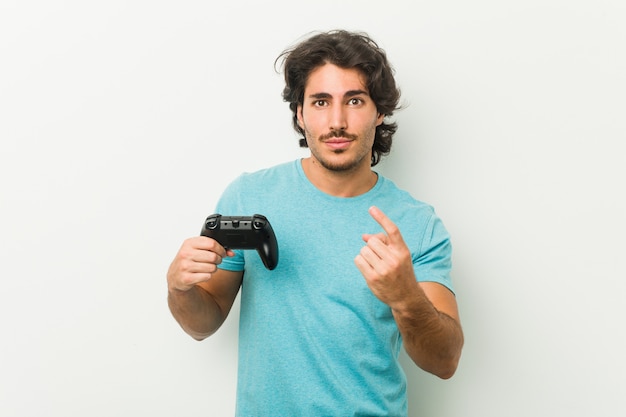 Young man holding a game controller pointing with finger