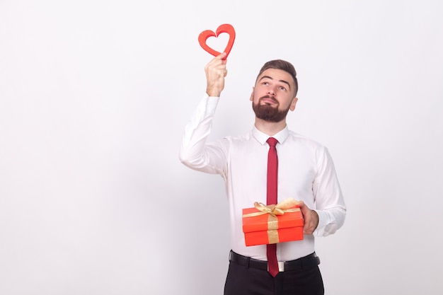 Young man holding gift box and dreaming of love