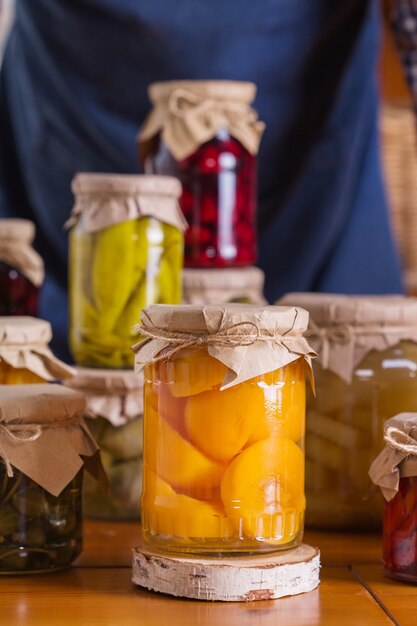 Foto giovane che tiene in mano barattoli con cibi conservati e fermentati fatti in casa, in salamoia e marinati. conservazione del raccolto, prodotti locali degli agricoltori