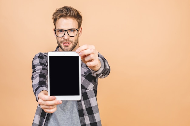 Young man holding in hands tablet computer with blank screen