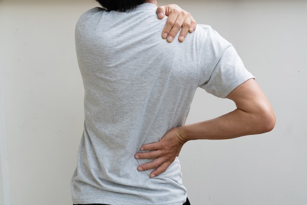 Photo young man holding his back in pain. medical concept