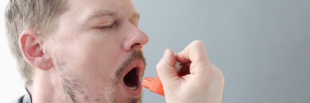 Young man holding his neck and inhaling medicine from inhaler treatment of bronchial asthma