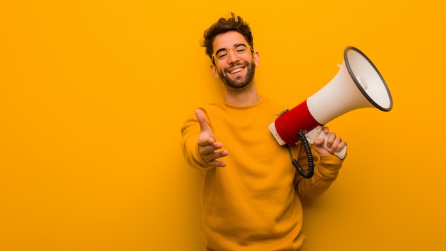 Young man holding a megaphone reaching out to greet someone