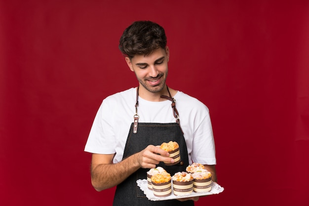 Young man holding mini cakes and surprised