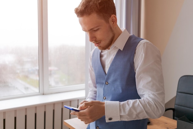 Young man holding mobile phone communicating and receiving text message reading