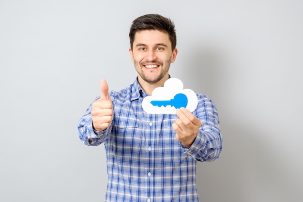 Young man holding model of cloud with blue key