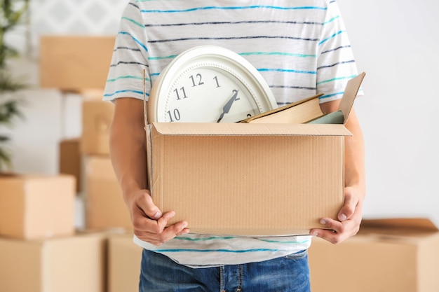 Young man holding moving box in room