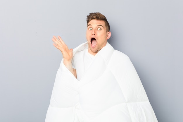 Young man holding a nordic duvet celebrating a victory or success