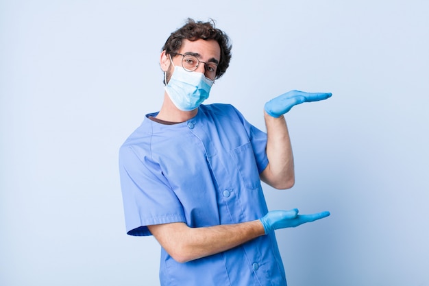 Young man holding an object with both hands on side copy space, showing, offering or advertising an object. coronavirus concept