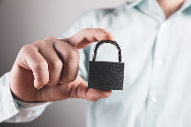 Photo young man holding a padlock in his hand.