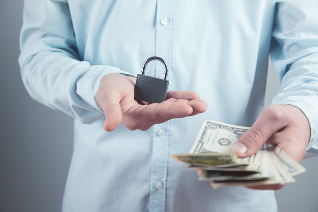 Young man holding a padlock and money