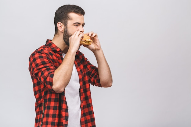 ハンバーガーの部分を保持している若い男。白い背景に対して隔離される食事概念。