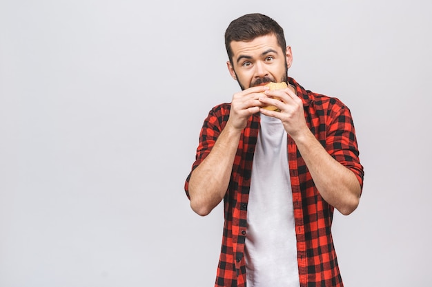 ハンバーガーの部分を保持している若い男。白い背景に対して隔離される食事概念。