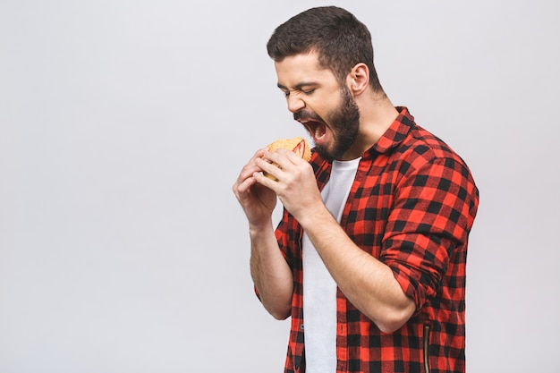 Giovane che tiene un pezzo di hamburger. concetto di dieta isolato su sfondo bianco.