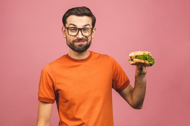 Young man holding a piece of hamburger. Student eats fast food. Very hungry guy. 