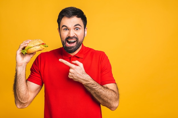 Young man holding a piece of sandwich. Student eats fast food. Burger is not helpful food.