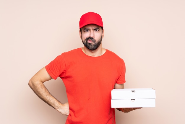 Young man holding a pizza angry