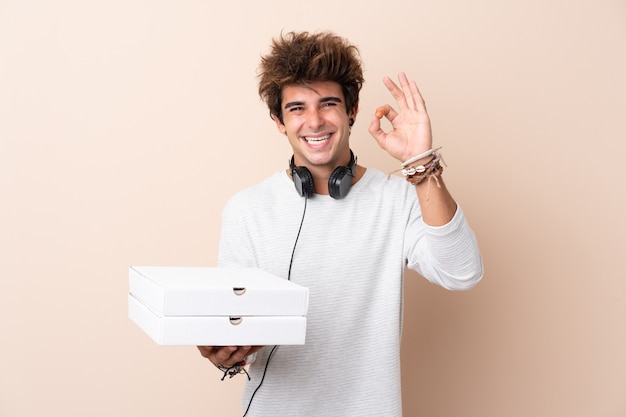 Young man holding pizza boxes over isolated wall