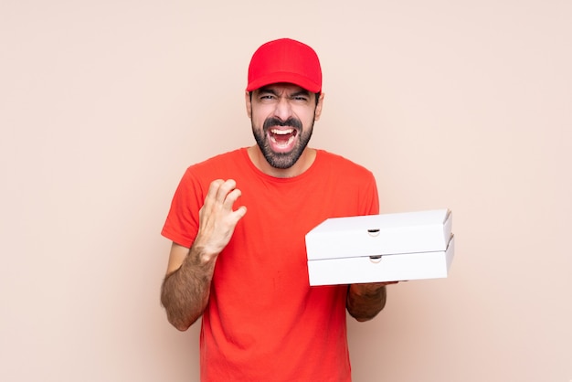 Young man holding a pizza frustrated by a bad situation