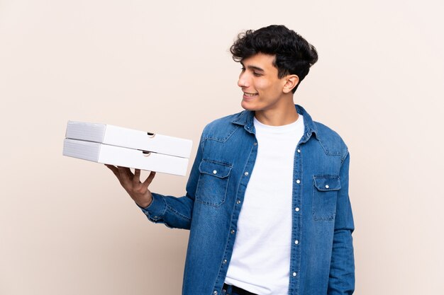 young man holding pizzas boxes over isolated wall